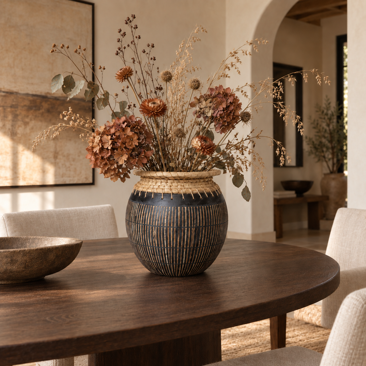 Jaylani black terracotta vase with rust-toned dried flowers in an organic modern dining room